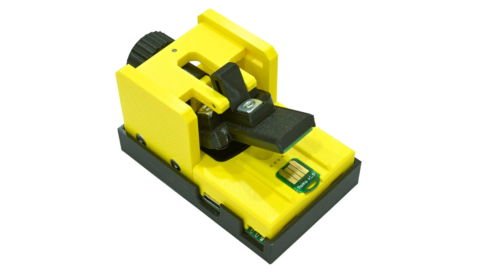 Yellow and black Romu programming and debugging jig with its clamp open above the board bed