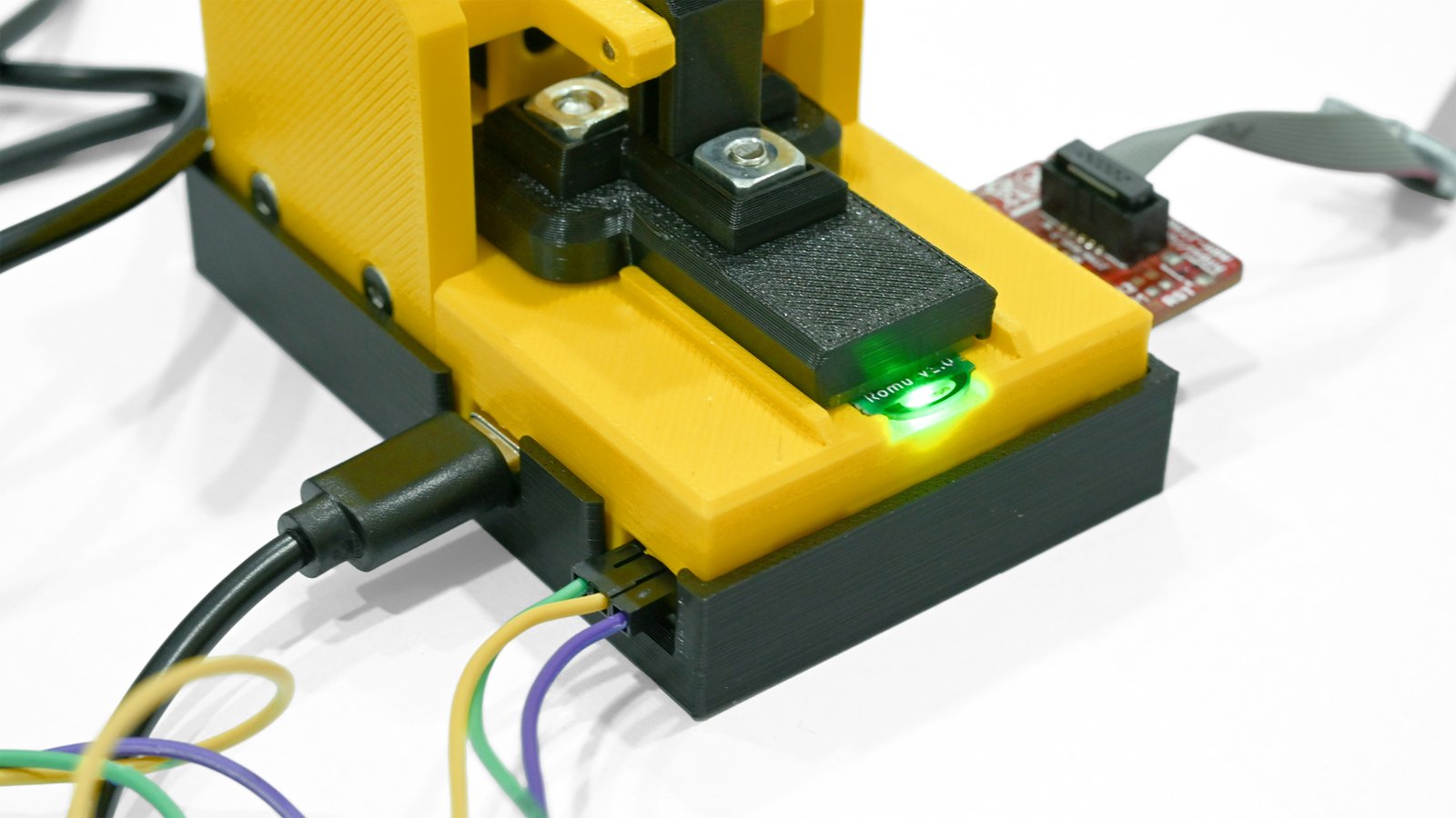 Romu held in its debugging jig with USB power, serial wiring and an external adapter connected