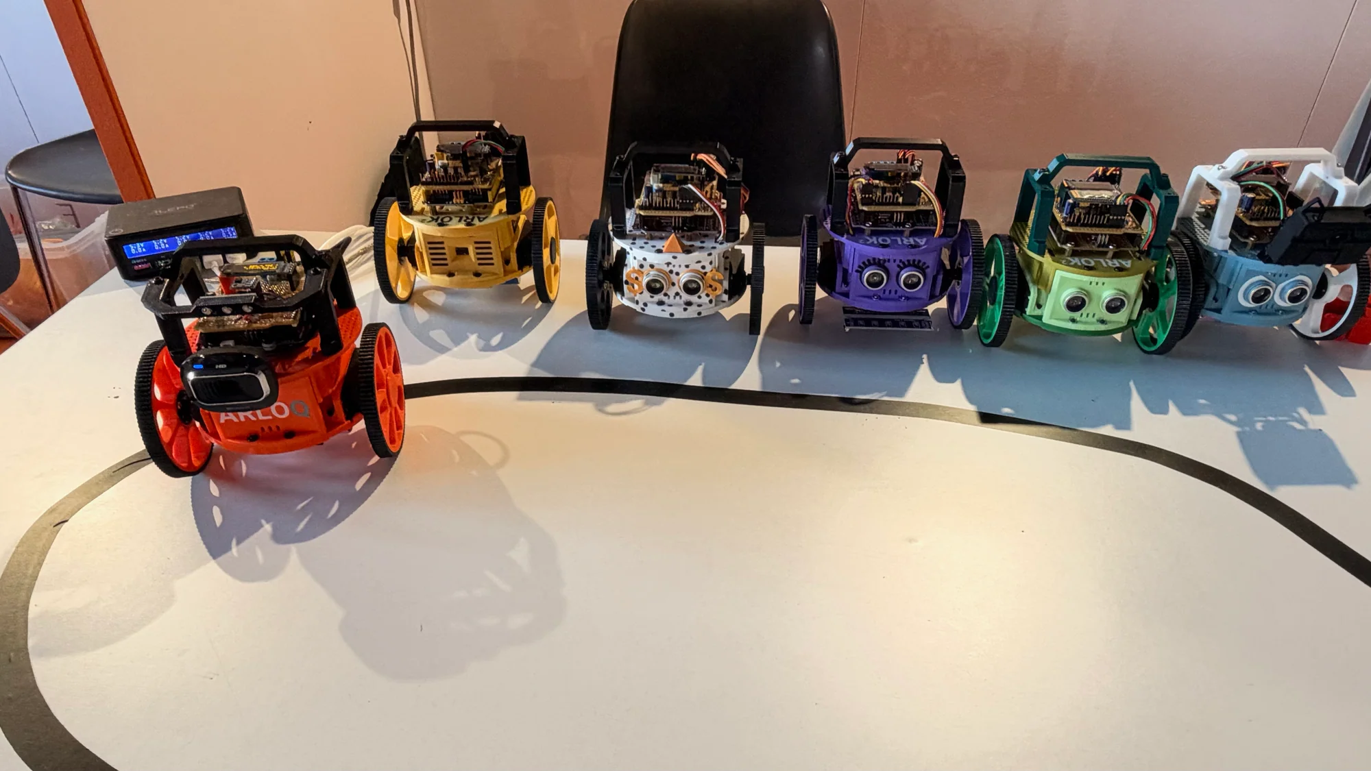 A row of colorful ARLOK V2 wheeled educational robots