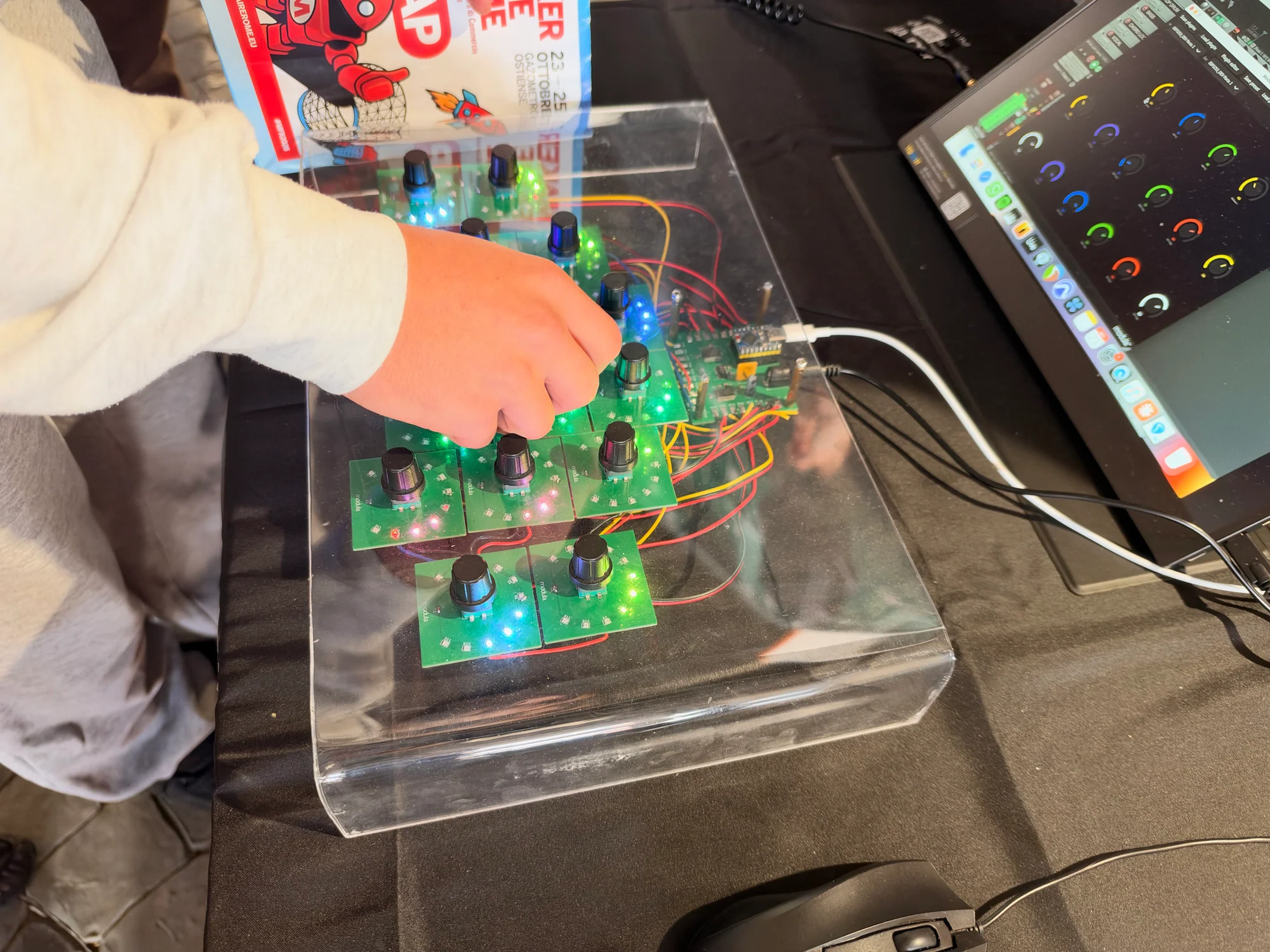 A visitor adjusting the controls on the Modula music interface beside a laptop