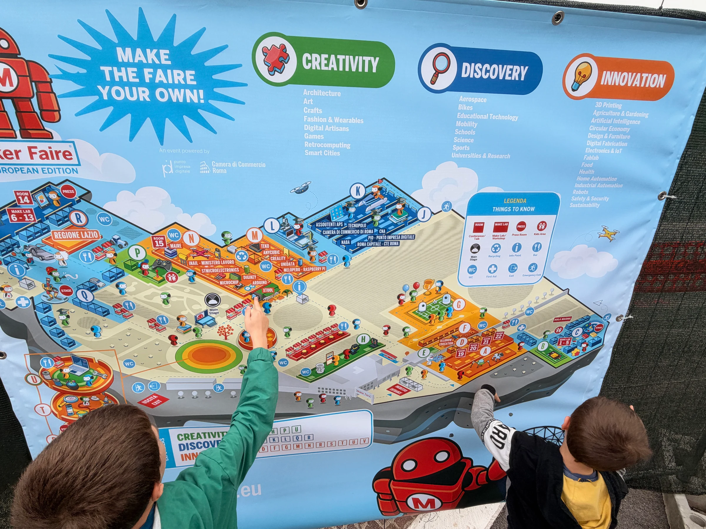 Visitors point out exhibitors on the illustrated Maker Faire Rome 2026 venue map.
